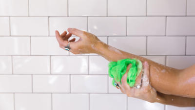 Woman Using Loofah to Moisturize Skin